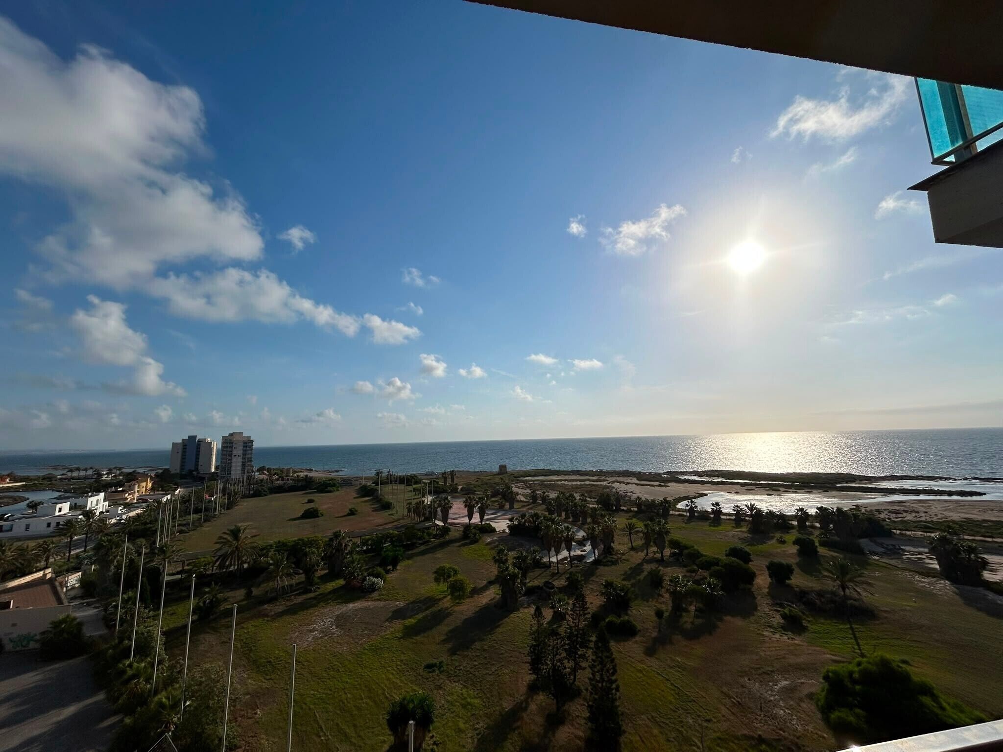 Une vue sur la côte, avec un ciel dégagé, une étendue d’eau et une silhouette de ville en arrière-plan.