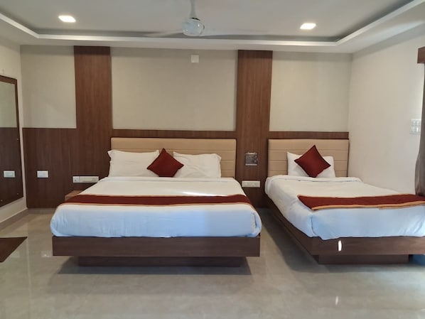 A hotel room with two beds, a wooden headboard, and a ceiling fan. - RRR Grand (Perundurai)