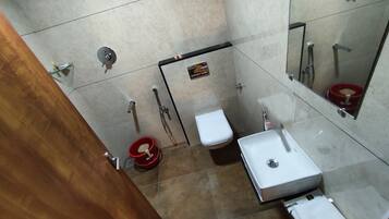 Casa de banho com sanita, lavatório e chuveiro.