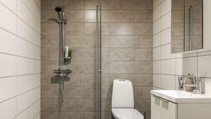 A modern bathroom with a shower, toilet, and sink.