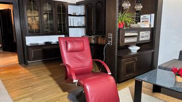 A modern living room with a red leather chair, dark wooden cabinets, and a glass coffee table.