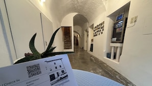 En gang med en QR-kode, en plante og et bord med et tjek-ind kort.