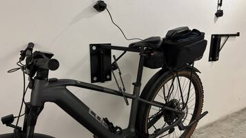 A stationary bicycle with a front-mounted device, a rear rack, and a black bag attached to the rear.
