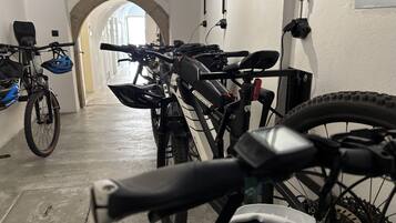 A bicycle storage area with multiple bikes, a concrete floor, and an arched doorway leading to another room.