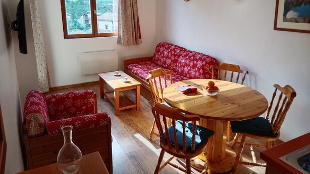Una stanza accogliente con un tavolo da pranzo in legno, sedie, un divano e una finestra con tende.