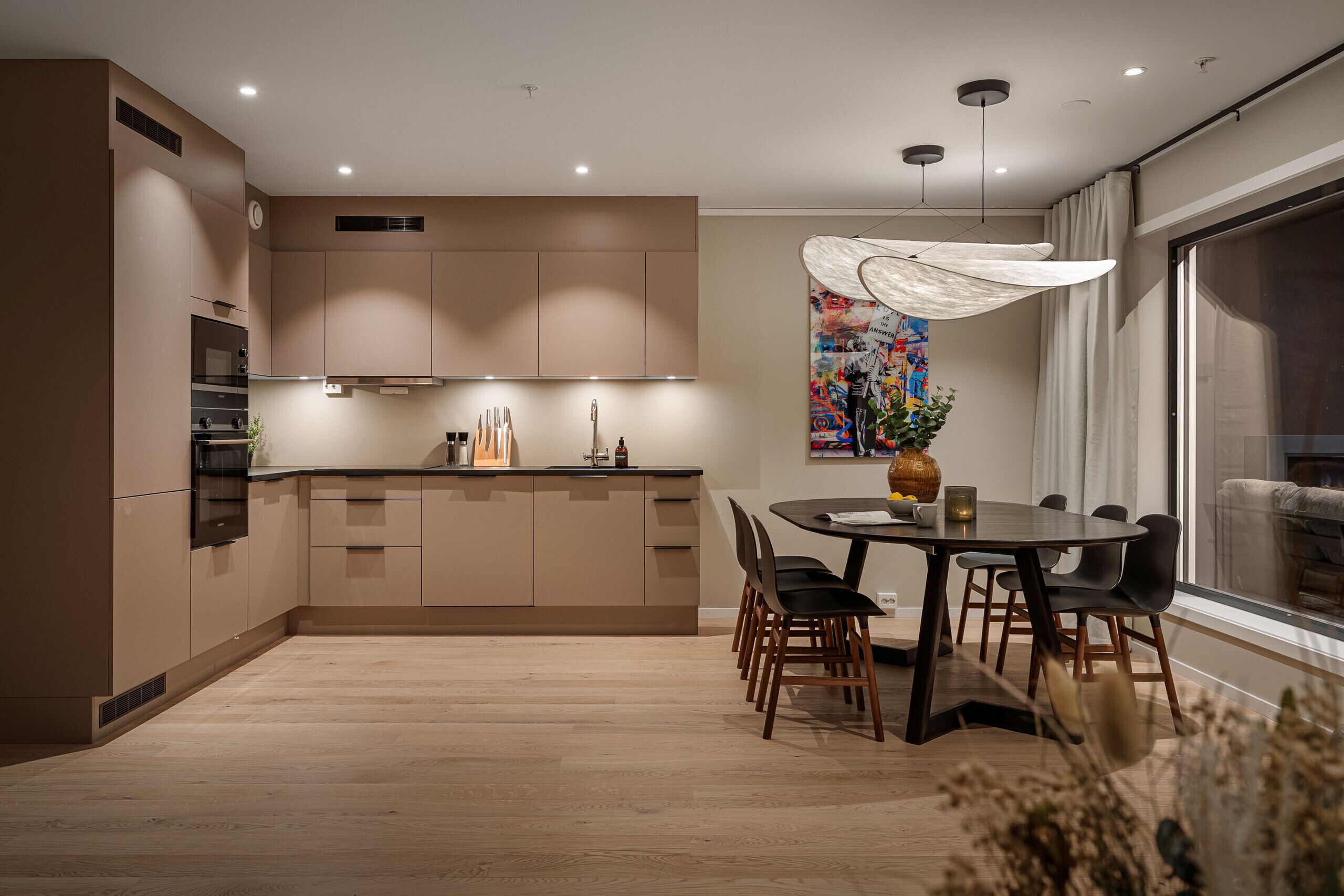 Una cocina moderna con armarios de madera, una mesa de comedor con sillas y un ventanal grande.