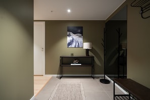 A modern interior with a console table, a lamp, and a bench. - Eight floor Premium Waterfront Penthouse (Tromsø)