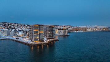 A waterfront hotel with modern architecture, a dock, and a view of the cityscape.