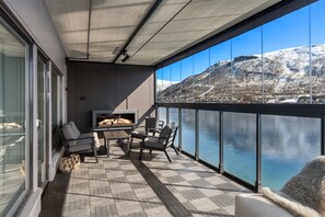 Ein Balkon mit kariertem Boden, einer Couch, einem Sessel und einem Fernseher.