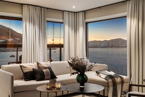 A modern living room with a sofa, a coffee table, and a vase. - Eight floor Premium Waterfront Penthouse (Tromsø)