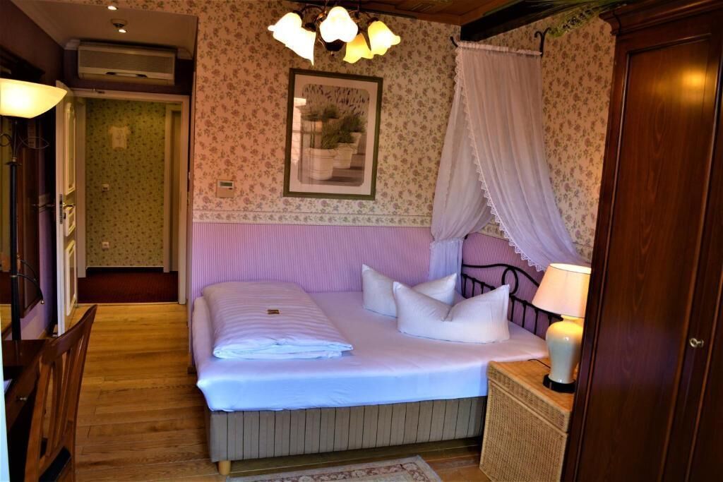 A bedroom with a bed, bedside table, lamp, and a picture on the wall.