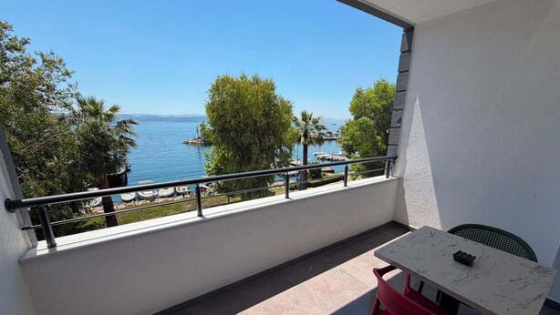 Un balcón con vista al mar, una mesa y una silla.