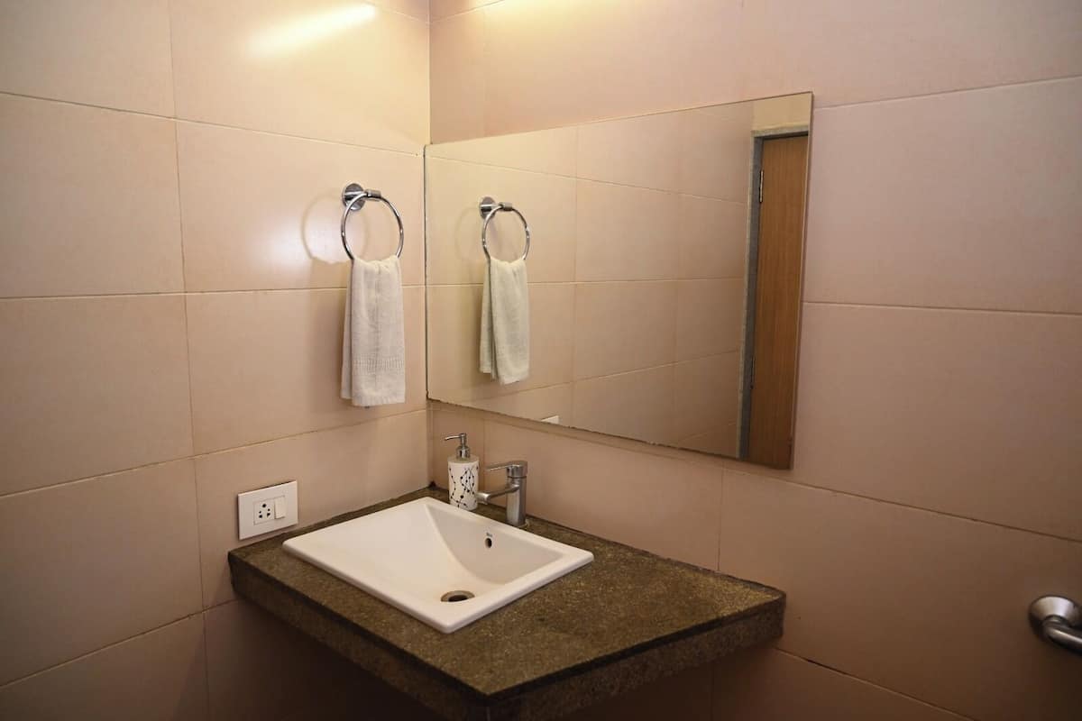 A bathroom with a white sink, a mirror, and two towels hanging on towel rings.