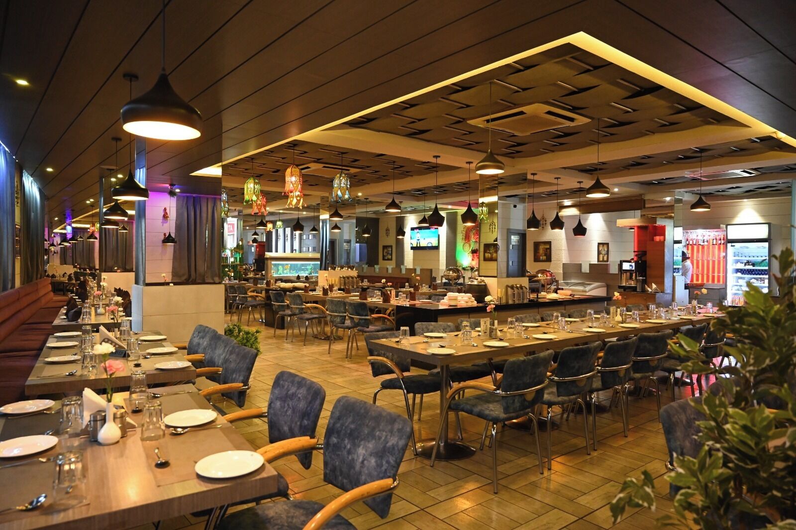 A spacious restaurant with multiple dining areas, a bar, and a kitchen visible in the background.