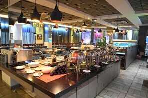 A buffet setup with multiple serving stations, a variety of dishes, and a modern interior design. - HOTEL GENISTA INN (Ranchi)
