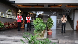 Entrada de hotel con un mostrador de recepción, plantas en macetas y una escalera.