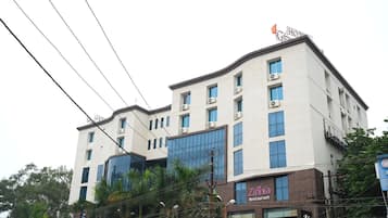 A multi-story hotel with a modern facade, air conditioning units, and a restaurant named 'Zinnia Restaurant' on the ground floor.