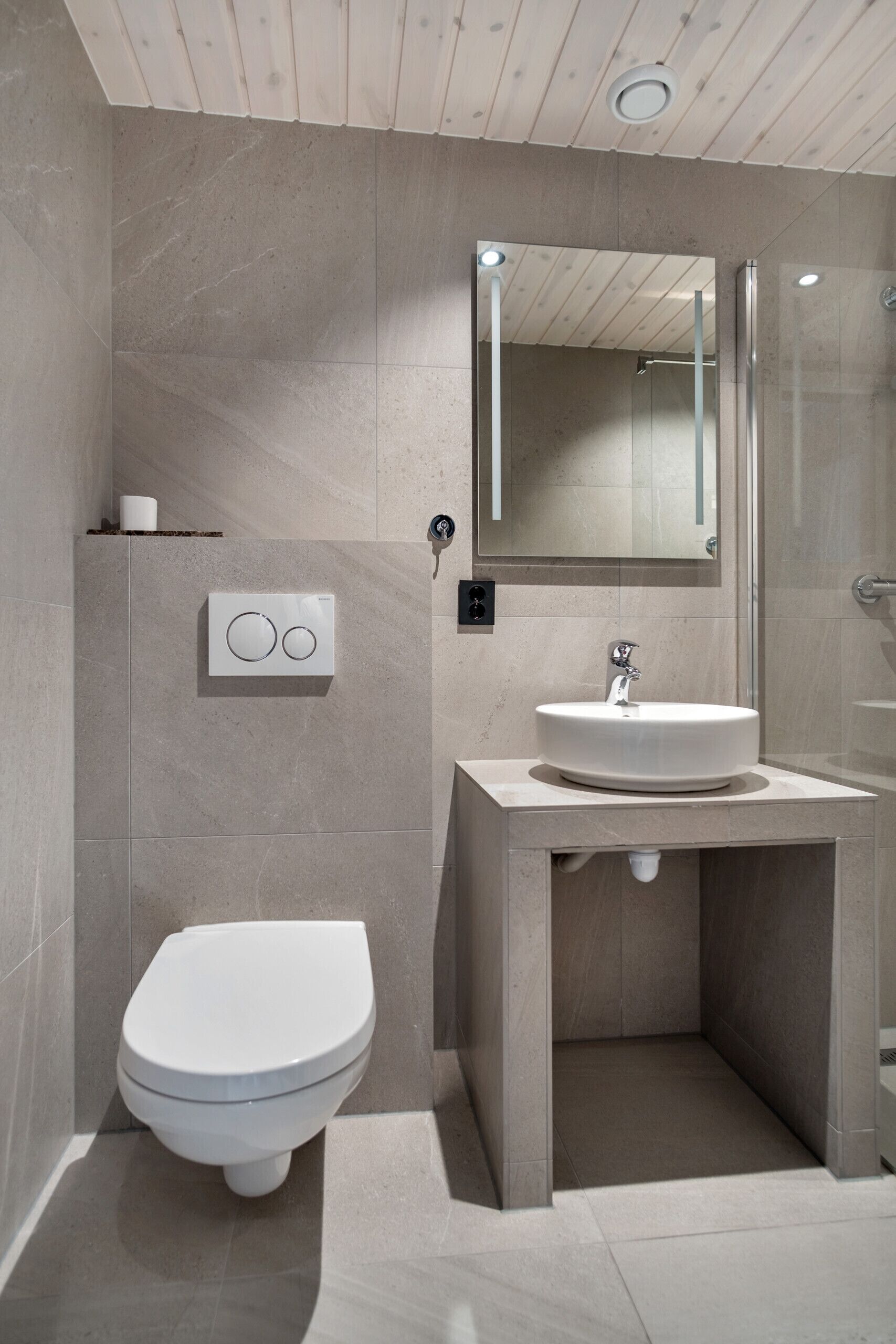 Une salle de bain moderne avec des toilettes, un lavabo et un miroir.