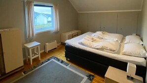 Una camera da letto con un letto, un tavolino, un termosifone e una finestra con tende.