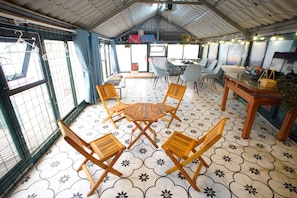 Ein Essbereich mit rundem Tisch und Stühlen, eine Bar mit Hockern und ein Blick durch ein großes Fenster.