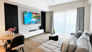 Ett modernt vardagsrum med en soffa, TV, matbord och en dekorativ vas.