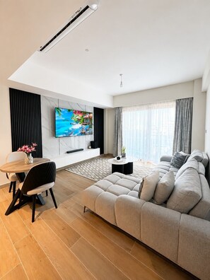 A modern living room with a sofa, TV, dining table, and a decorative vase. - Stylish 1BR in Nyali with Pool, WiFi & Beach Access (Mombasa)