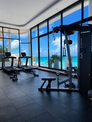 A gym with exercise equipment, large windows, and a view of the ocean. - Stylish 1BR in Nyali with Pool, WiFi & Beach Access (Mombasa)