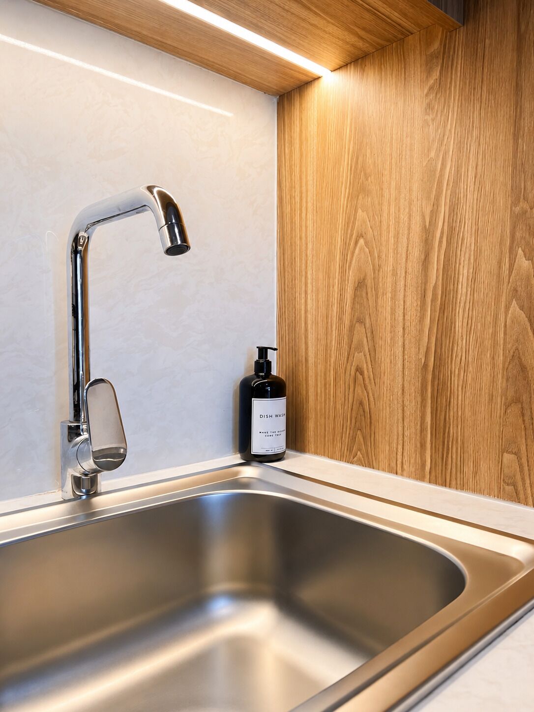 A modern kitchen with a stainless steel sink, a chrome faucet, and a bottle of dish soap.