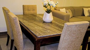 A dining table with a vase of flowers, surrounded by upholstered chairs. - Wide breathtaking Sea View Apartment (Alexandria Governorate)