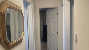 A hallway with a wooden floor, white walls, and a mirror on the left. - Spacious 4-bedroom building with AC in amazing Pittsburg (Pittsburg)