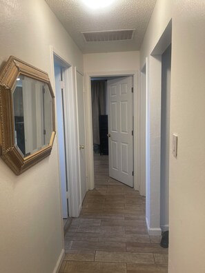A hallway with a wooden floor, white walls, and a mirror on the left. - Spacious 4-bedroom building with AC in amazing Pittsburg (Pittsburg)