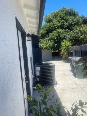 A residential area with a white house, an air conditioning unit, a tree, and a trash bin. - Spacious 4-bedroom building with AC in amazing Pittsburg (Pittsburg)
