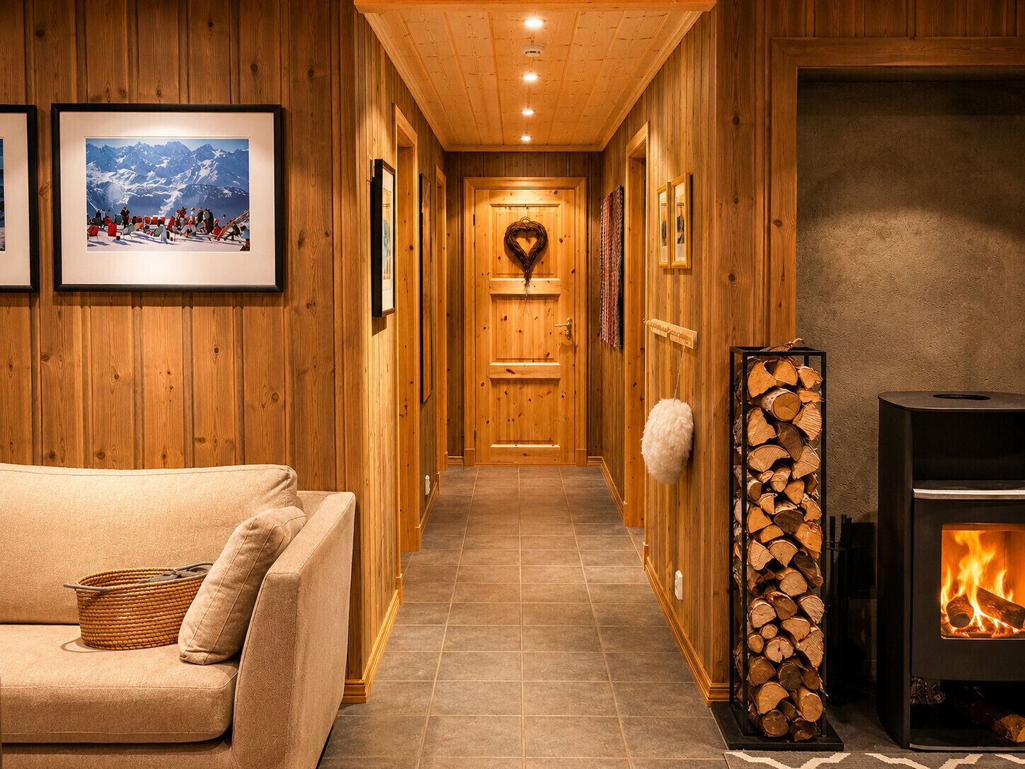 Un couloir en bois avec un canapé, des tableaux encadrés, une cheminée et une pile de bois de chauffage.