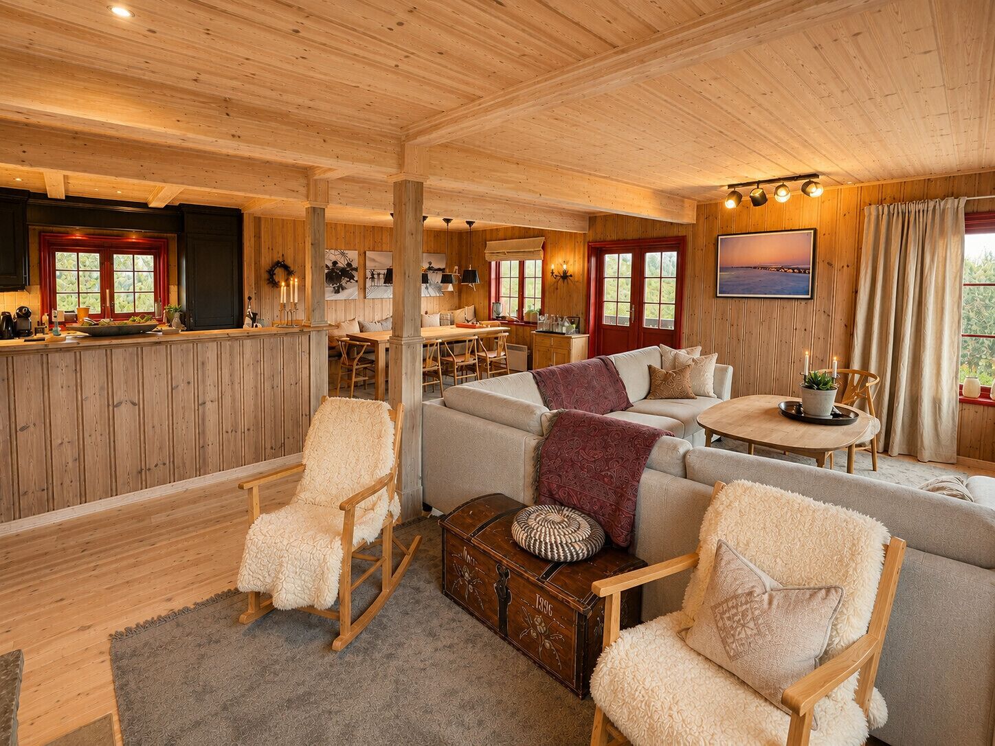 Een gezellig interieur van een chalet met een eethoek, een bank, schommelstoelen en uitzicht op de natuur.