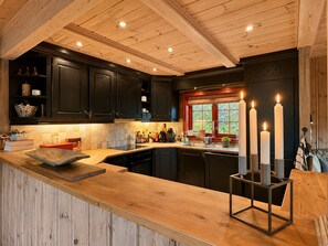 A kitchen with dark cabinets, a wooden countertop, and a window with a view. - Spacious cabin with beautiful Geilo views (Hol)
