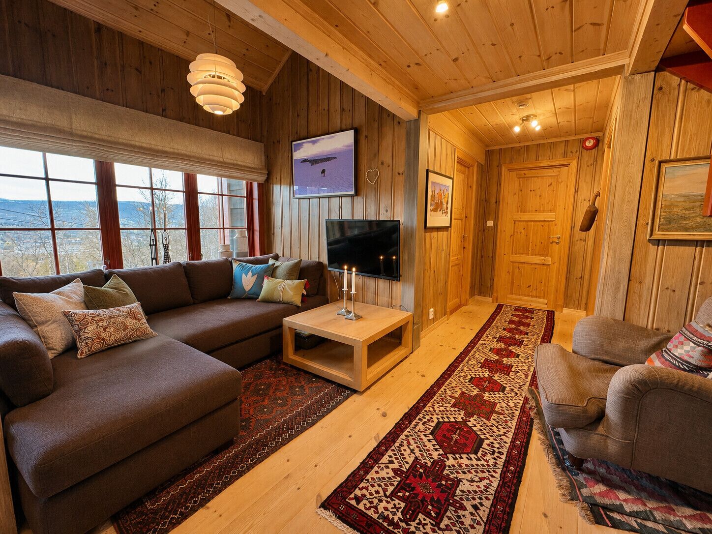 Een gezellige woonkamer met een bank, televisie en houten wanden.