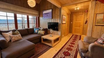 Een gezellige woonkamer met een bank, televisie en houten wanden.