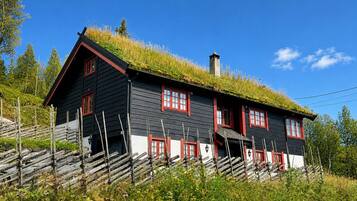 Et traditionelt træhus med græstag og røde vinduesrammer.