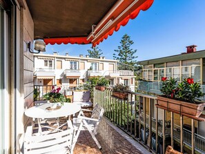 A balcony with a table and chairs, potted plants, and a view of neighboring buildings. - Luna Verde by Interhome (Sanremo)