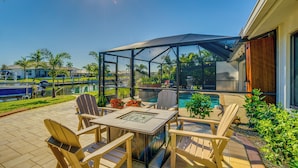 Eine Terrasse mit Gartenmöbeln, einer Glasveranda und einem Pool.