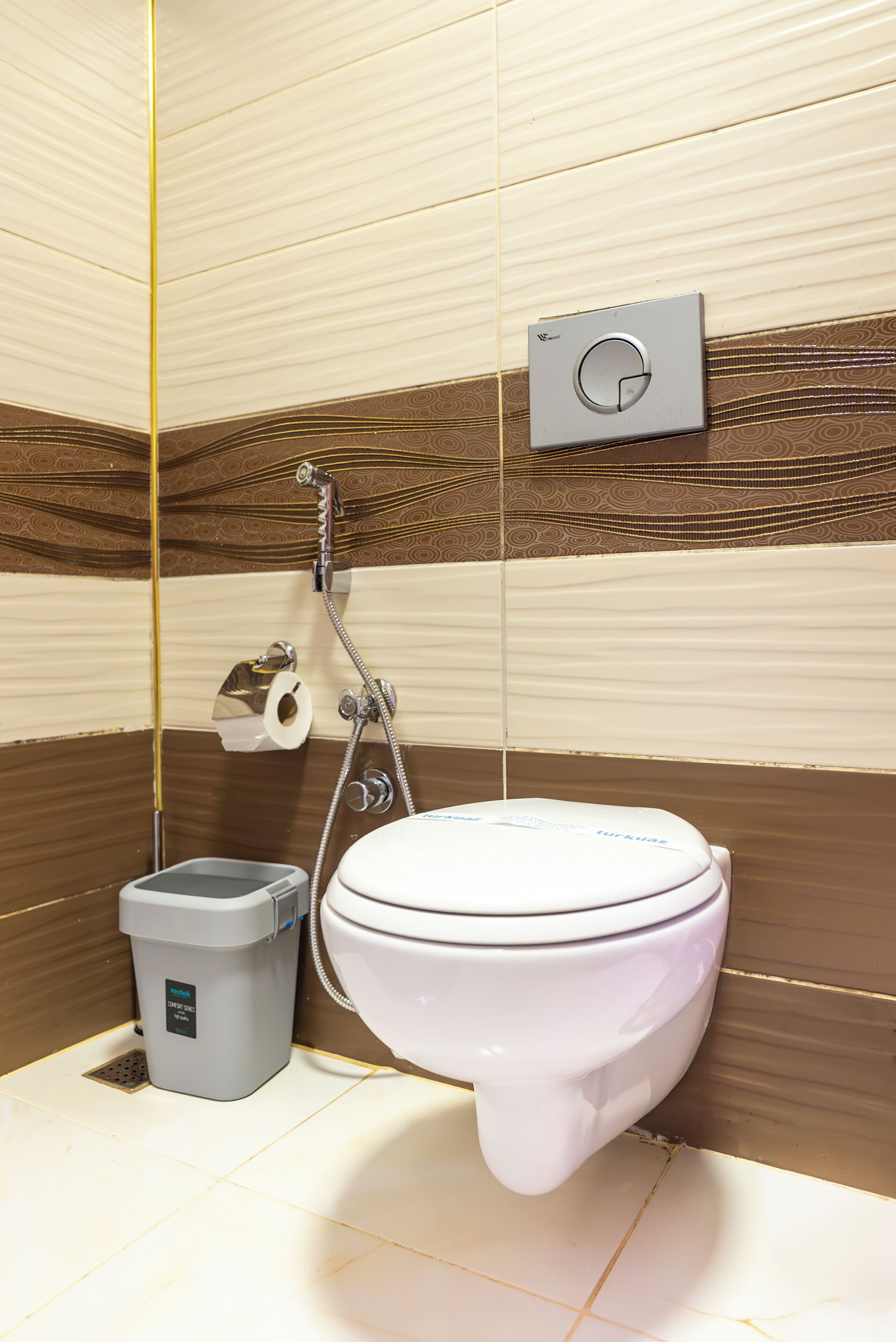A bathroom with a toilet, a trash bin, and a shower.