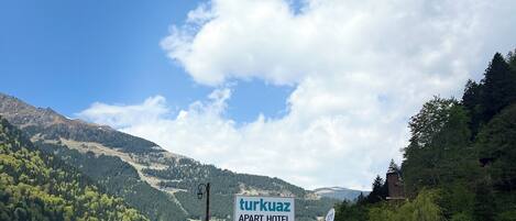A reception area with a sign for 'Turkuaz Apart Hotel' and a mountain backdrop.