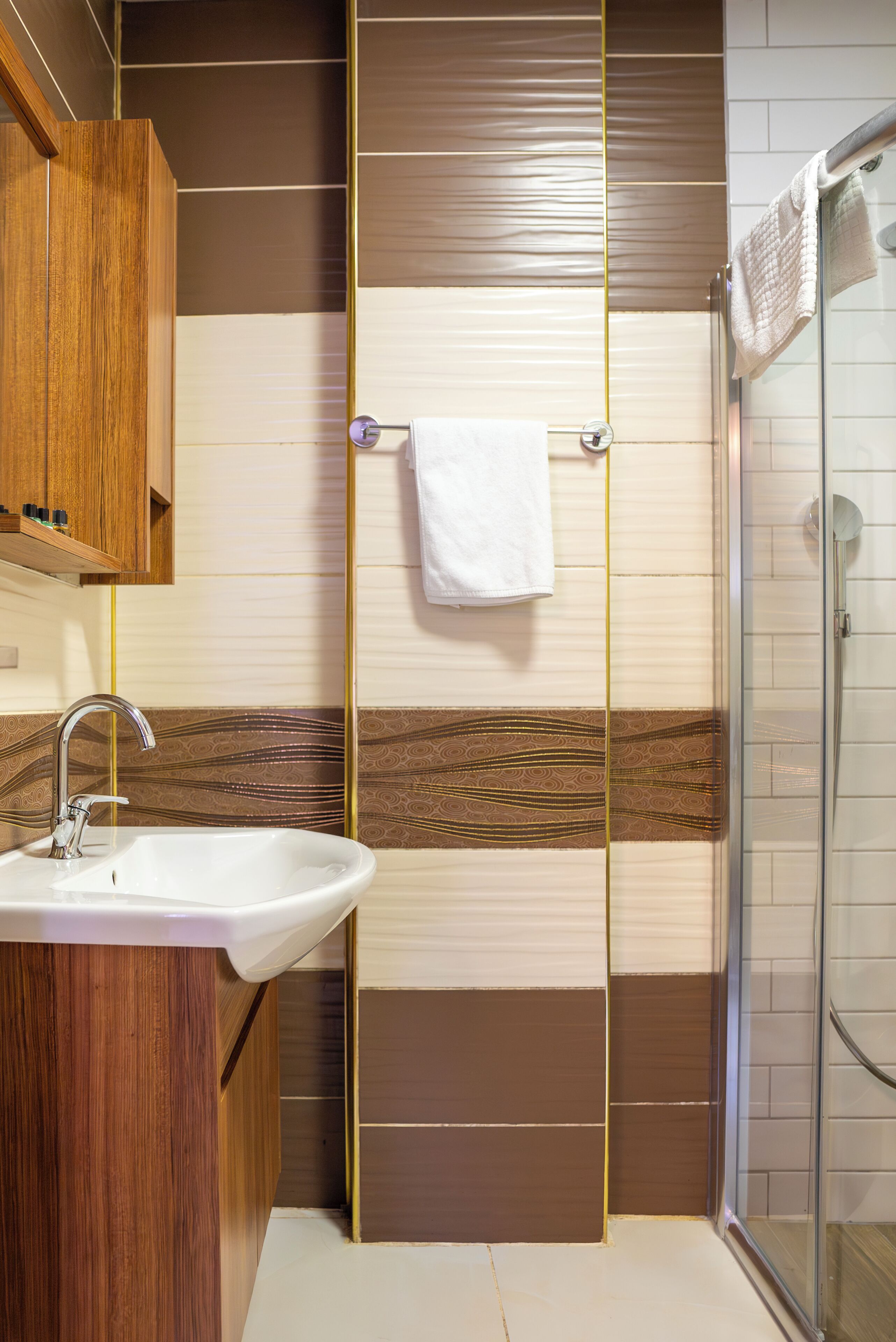 A bathroom with a wooden vanity, a sink, a towel rack, and a glass shower enclosure.