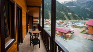 A wooden balcony with a view of a mountainous landscape and a parking area. - TURKUAZ APART HOTEL (ÇAYKARA)
