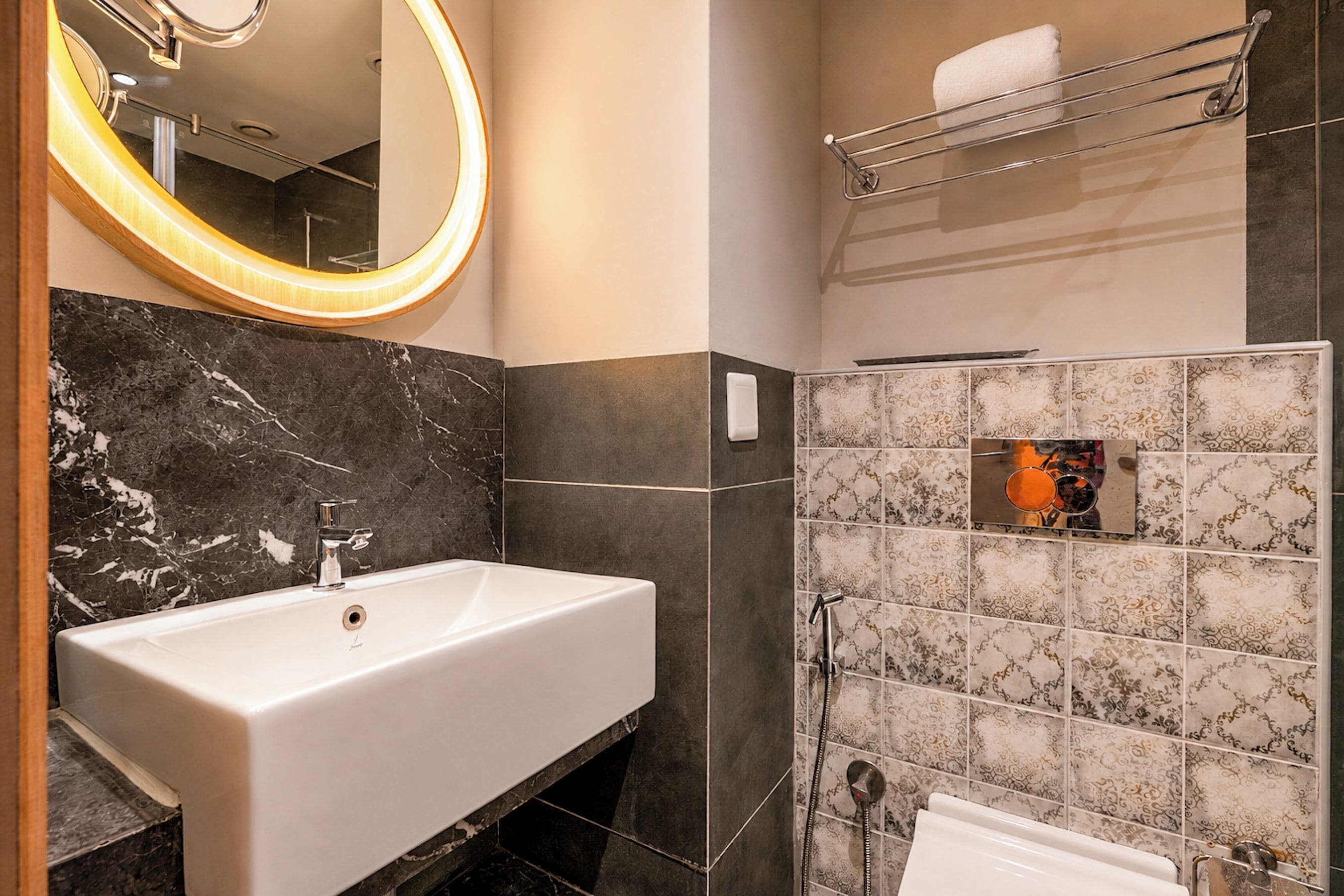 A bathroom with a white sink, a mirror with a light, and a shower area.