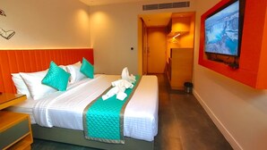 Quarto de hotel com cama, televisão e banheiro visível por uma porta aberta.