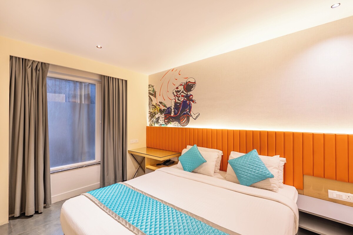 A hotel room with a bed, a desk, and a window with curtains.