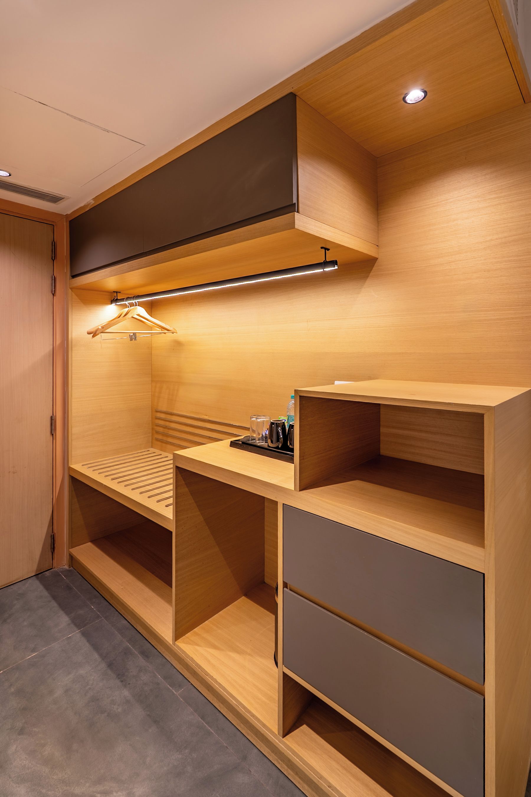 A compact, modern room with built-in shelving, a desk, and a hanging light fixture.