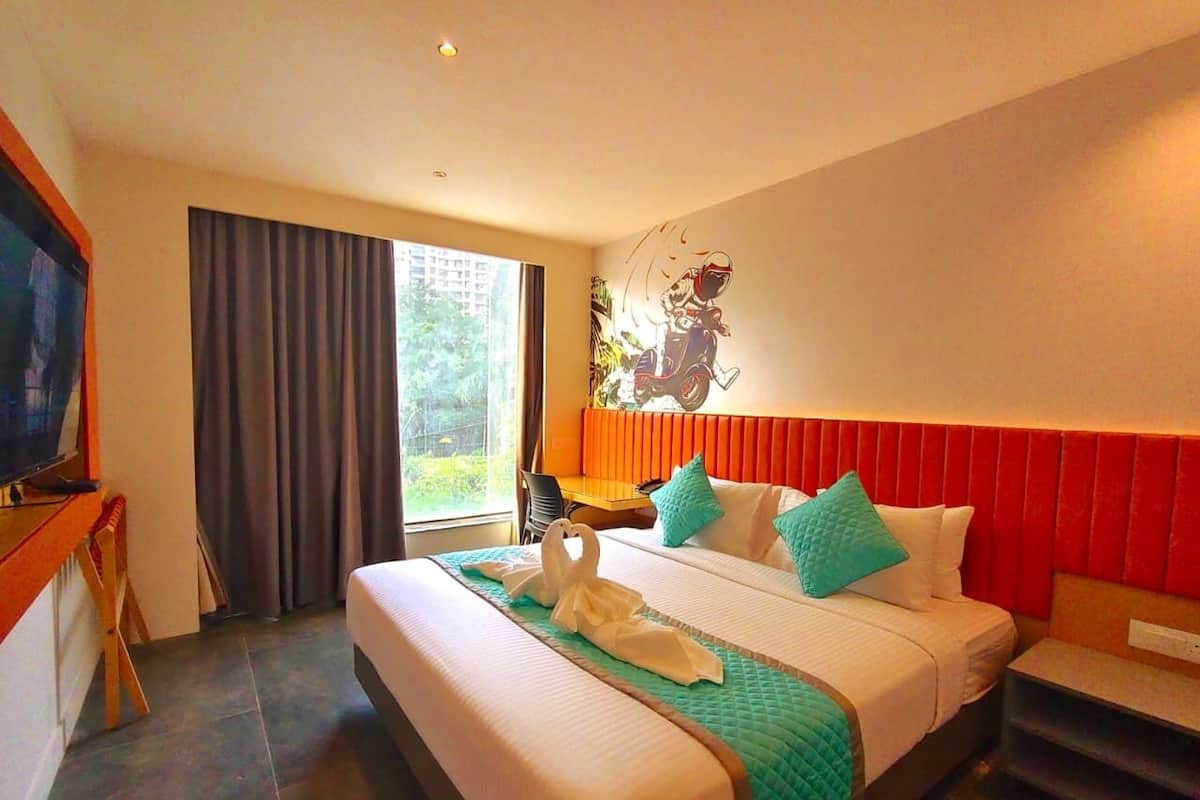 Habitación de hotel con una cama grande, un escritorio, un televisor y vistas a zonas verdes.