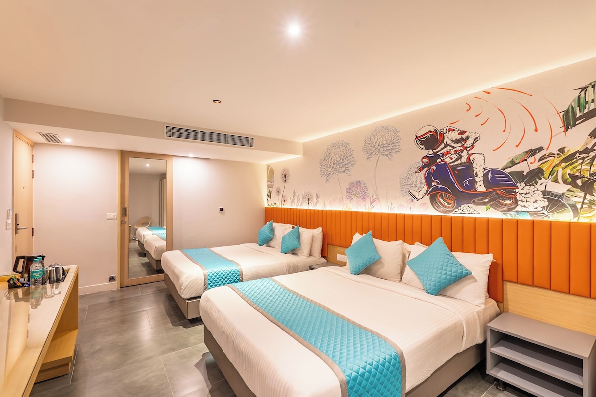 A hotel room with two beds, a desk, and a wall mural.